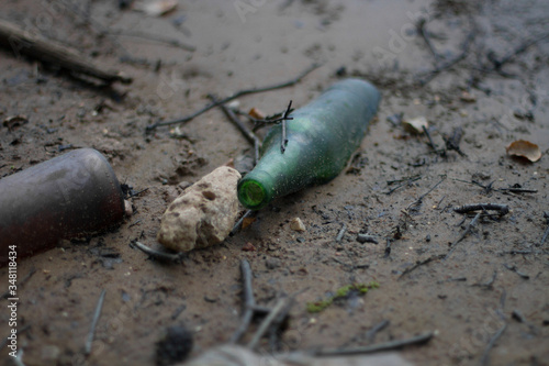 Empty glass bottle in the sand. Dirty beach. Dirty seashore. Ecology concept.