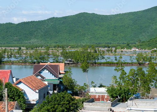 Vietnamese View on the house, water-filled rice paddies and mountains covered with vegetation on a sunny day
