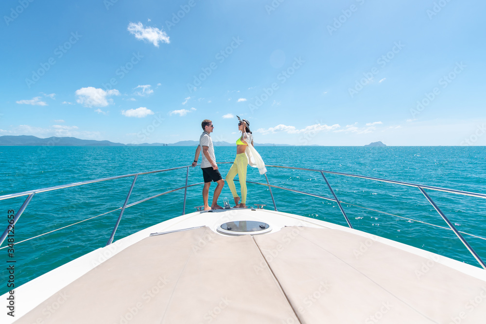  sweet couple standing on edge of luxury yacht. Brunette wearing straw hat and fashion summer suit and  sunglasses.