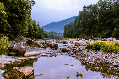 Mountain landscape. Mountain river among the rocky shores. Around the mountains and the forest.