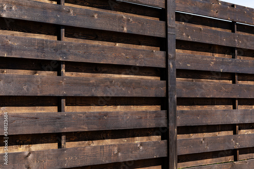 A fragment of a strong wooden fence. Horizontal boards are tightly nailed to each other and provide reliable protection from robbers.