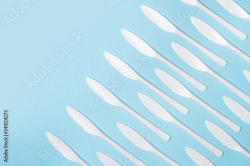 Cuchillos blancos desechables de plástico sobre un fondo celeste liso aislado. Vista superior. Copy space. Concepto: patrón repetición