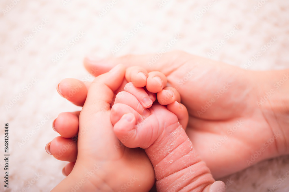 Mother gently hold baby leg in hand. Slightly toned image with soft focus. Parental hand holds hand the baby. Mother gently hold baby leg in hand. Slightly toned image with soft focus. Parental hand holds hand the baby.