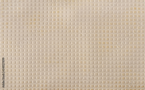 Beige faux leather with a pattern of evenly repeating small circles. A variety of textures of artificial materials. Background.