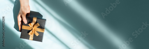Web banner with gift box in a female hand on sunlights. Flat lay, top view, place for text.