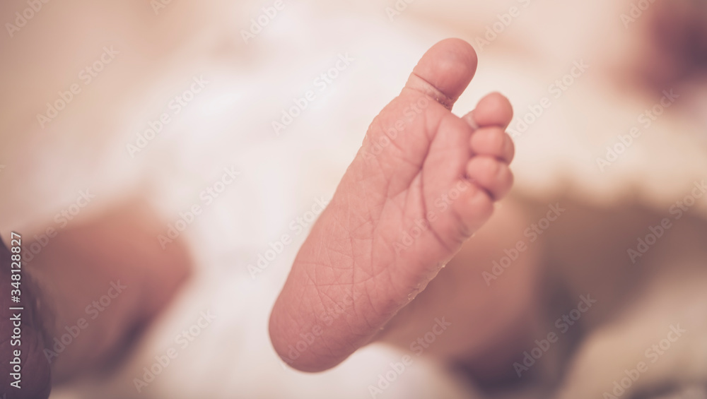 Newborn feet. Sweet baby in a gentle morning light on the bed. Bare feet of a cute newborn baby in warm white blanket. Childhood. Small bare feet of a little baby girl or boy. Sleeping newborn child. Newborn feet. Sweet baby in a gentle morning light on the bed. Bare feet of a cute newborn baby in warm white blanket. Childhood. Small bare feet of a little baby girl or boy. Sleeping newborn child.