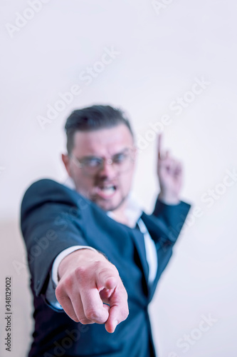 Very angry businessman pointing at You and up on free copy space. Selective focus.