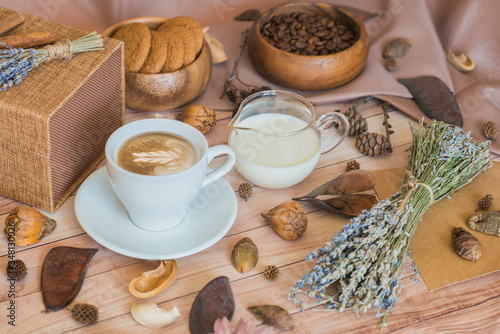 A cup of coffee, milk, coffee beans, oatmeal cookies on a wooden background. Cozy autumn composition. Morning breakfast. Autumn mood