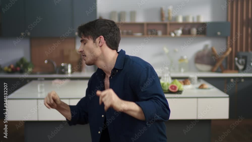 Attractive man dancing at home kitchen. Sexy man in open skirt posing to camera