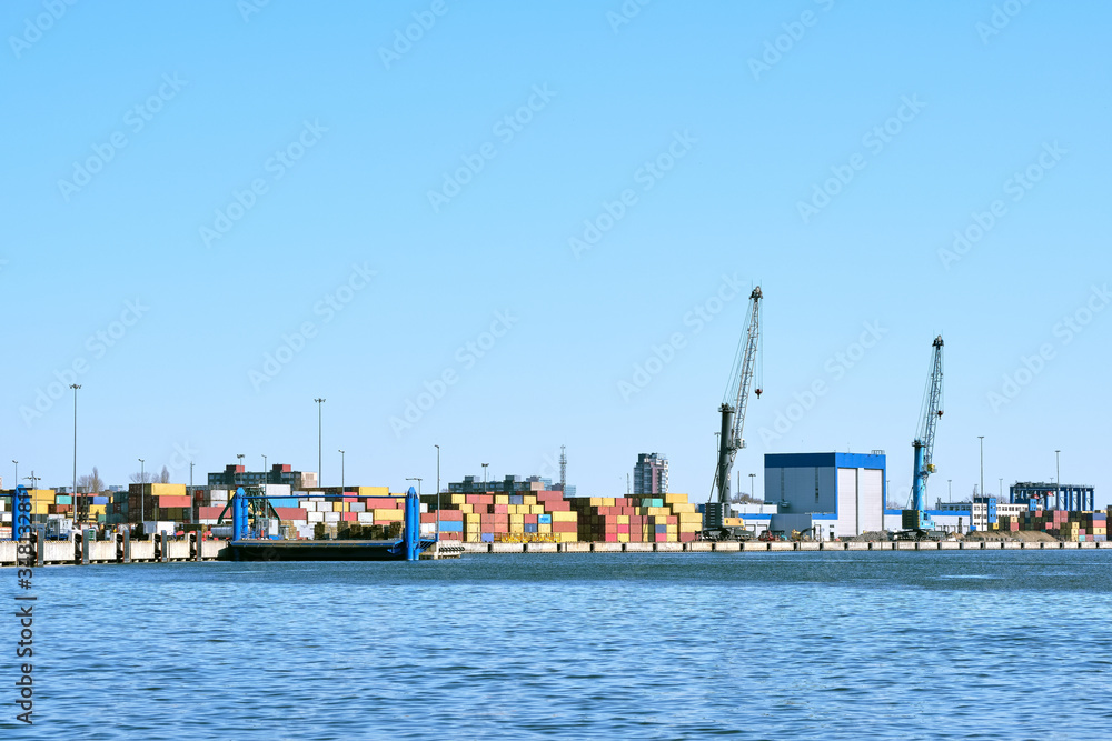 View of port cranes, loading bridges and container terminal on clear sunny day and cloudless sky. Sea trade, transportation, commerce and cargo