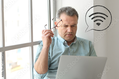 Mature man with laptop usin...