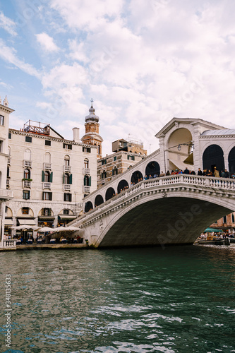The beautiful Ponte di Rialto Bridge over the Central Grand Canal in Venice, Italy, with shops, beautiful views and lots of people. Near boat station of the same name, the street leads to San Marco