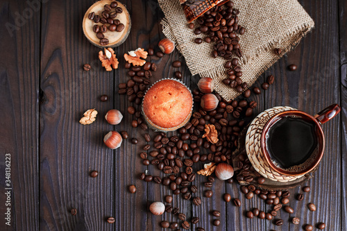 hot fragrant coffee in a vintage clay cup and coffee beans with nuts on a dark wooden background © Алена Румянцева