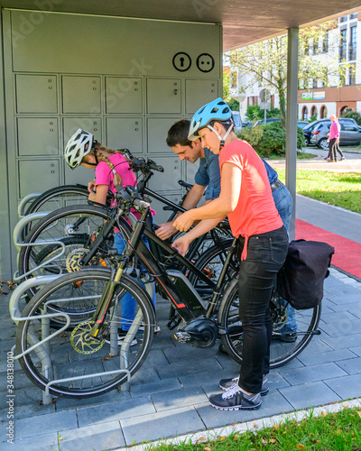 Gutgelaunte Familie nutzt ein vorbildliches Fahrrad-Abstellkonzept für einen Stadtbummel zu Fuß