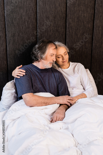 mature couple hugging and smiling in bed