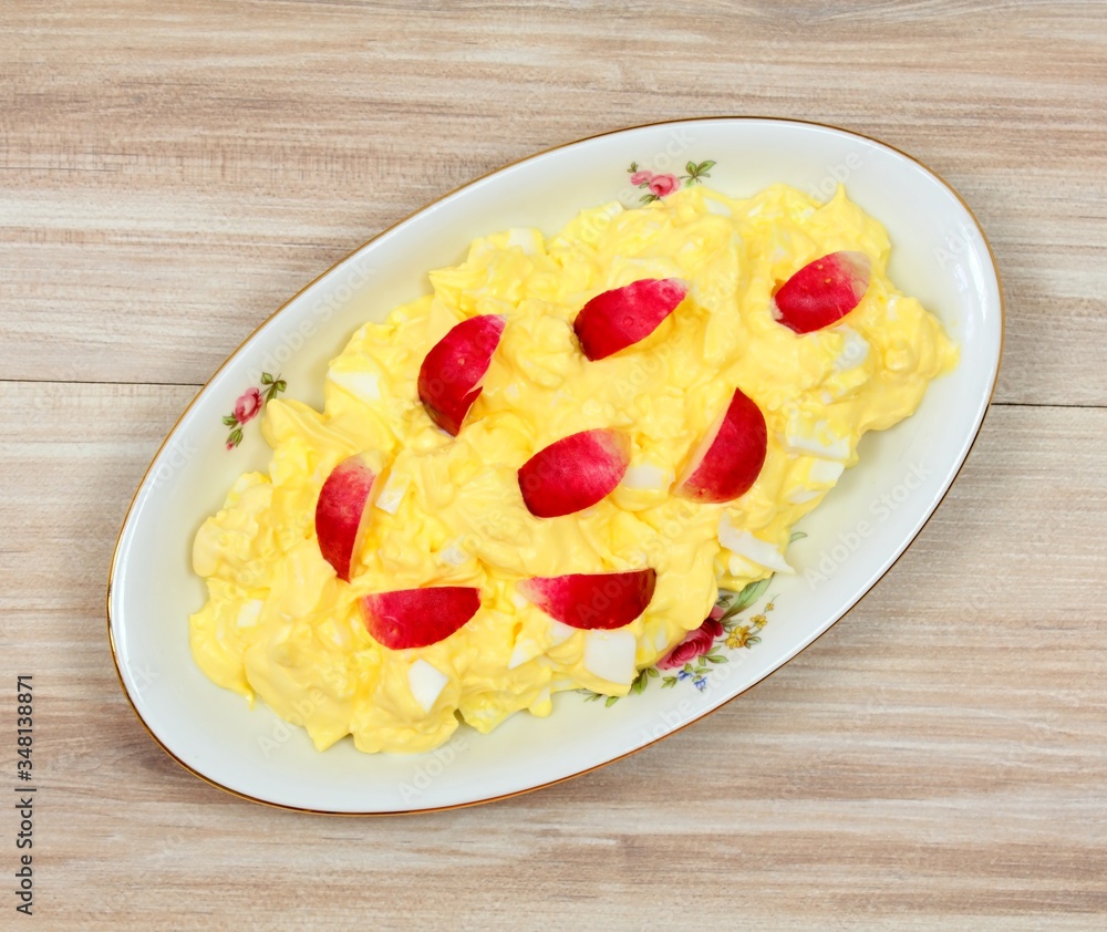 Egg salad on the plate with radish, top view. Homemade salad made from eggs and mayonnaise on wooden table. Egg salad on the plate with radish, top view. Homemade salad made from eggs and mayonnaise on wooden table.