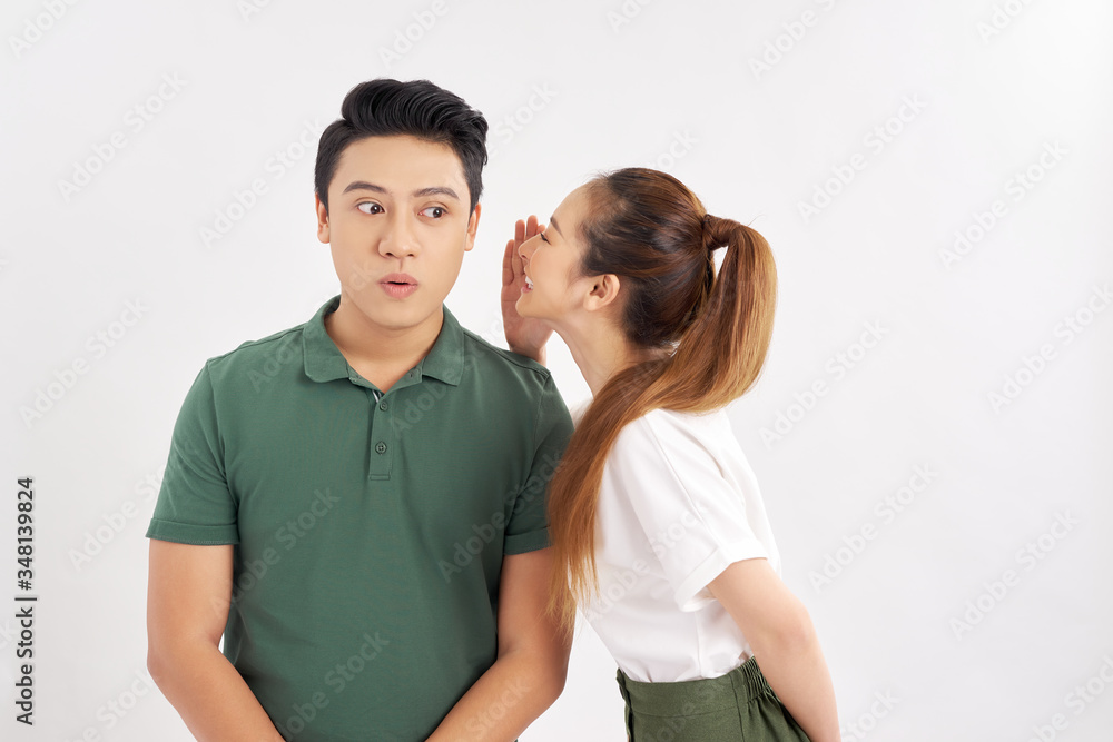 Portrait of attractive woman talking to handsome man in his ear isolated over white background Portrait of attractive woman talking to handsome man in his ear isolated over white background