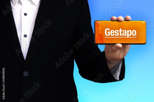 Gestapo. Anwalt zeigt ein Handy. Auf dem Display steht ein Wort. Blauer Hintergrund. Hand hält Telefon. Recht, Gesetz