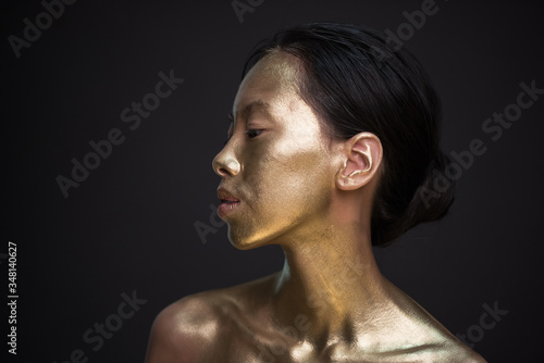 Portrait of young asian woman in golden paint