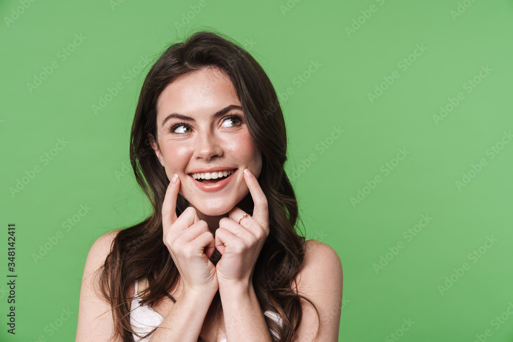 Image of happy woman smiling and pointing fingers at her cheeks Image of happy woman smiling and pointing fingers at her cheeks