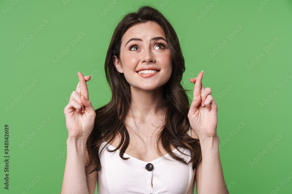 Image of pleased young woman posing with fingers crossed for good luck Image of pleased young woman posing with fingers crossed for good luck