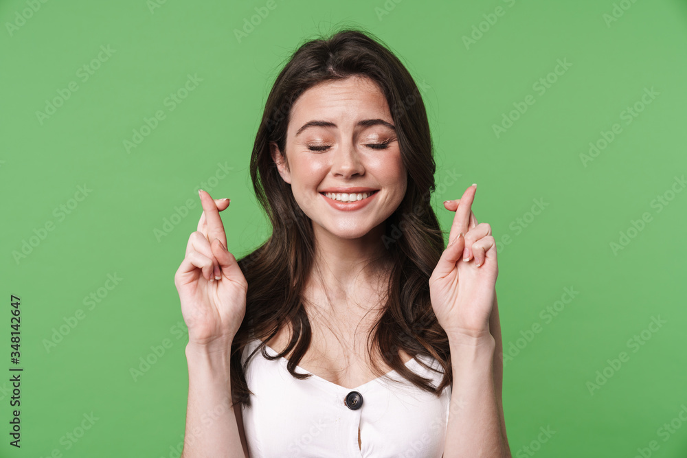 Image of pleased young woman posing with fingers crossed for good luck Image of pleased young woman posing with fingers crossed for good luck