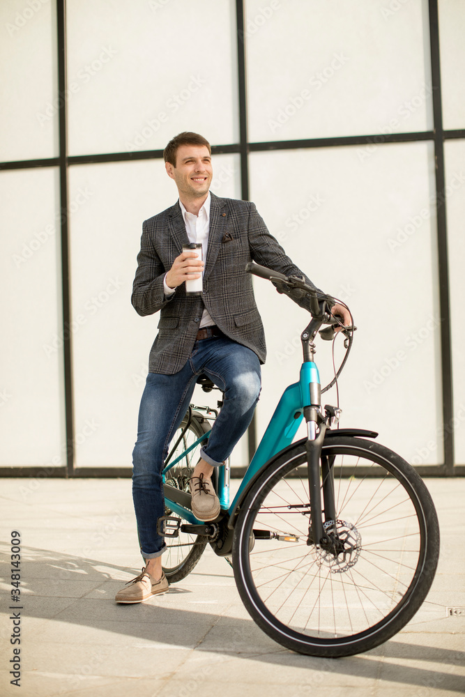 Young businessman on the ebike with takeaway coffee cup Young businessman on the ebike with takeaway coffee cup