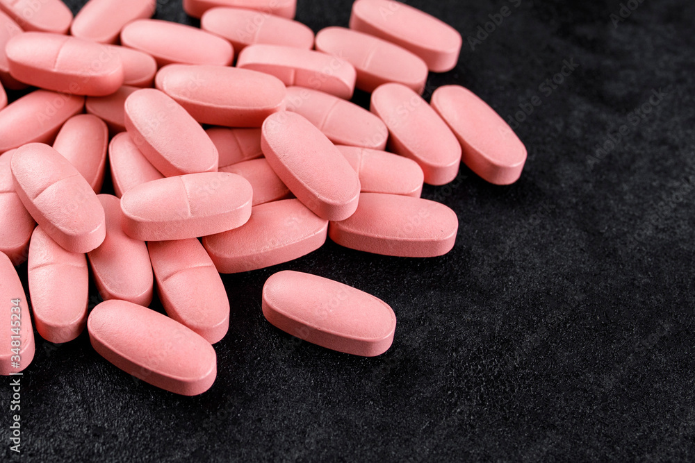 pink pills on a black background pink pills on a black background