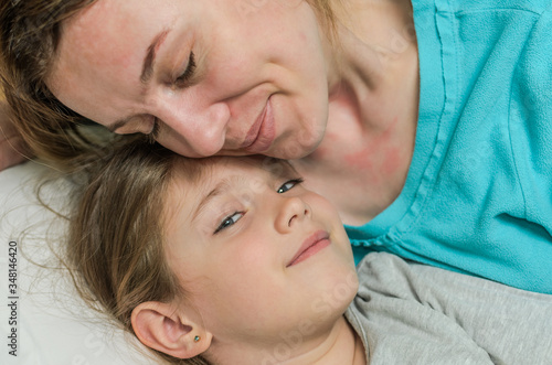 Young mother and daughter lie in bed on a pillow and hugging, happy family © Cliff