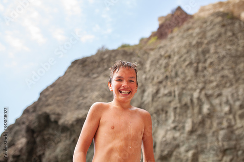 Portrait of a happy boy after swimming in the sea, drops are falling down his face, a teenager is cheerful and laughing © rimmdream