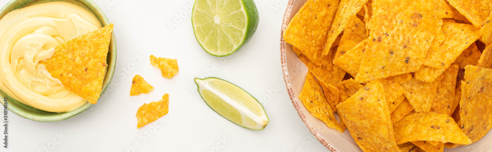 top view of corn nachos with lime and cheese sauce on white background, panoramic shot top view of corn nachos with lime and cheese sauce on white background, panoramic shot