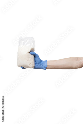 plastic bag hold in hand isolated on white background. man wearing blue gloves holding pack of sugar. delivery during quarantine of coronavirus pandemic COVID-19. food supplies, donation, volunteer