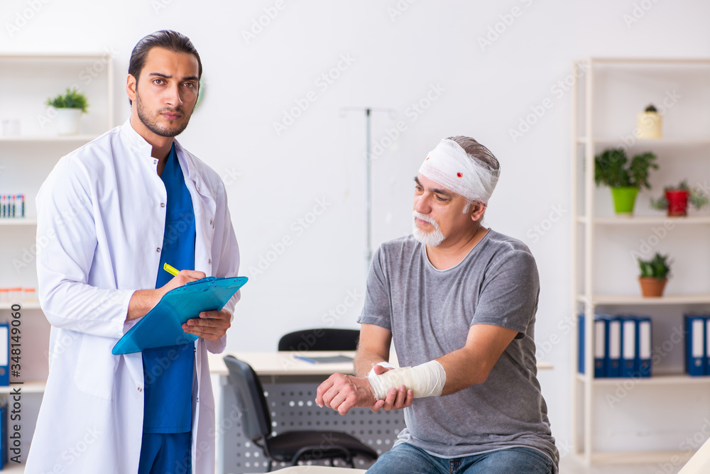 Young male doctor and old patient in first aid concept Young male doctor and old patient in first aid concept