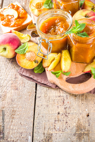 Homemade peach jam in different jars, with fresh organic peaches on wooden rustic background copy space