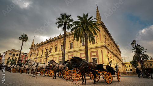 Seville, Spain - February 7th, 2020 - Parked horse-drawn carriages in front of the General Archive of the Indies in Seville City Center, Spain.