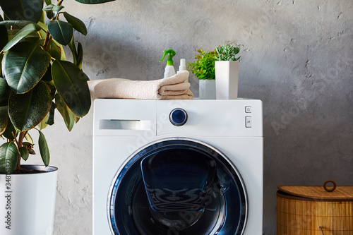 Valokuva plants, towel and bottles on washing machine near laundry basket in bathroom
