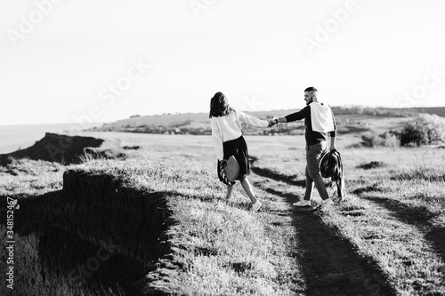 A guy and a girl love each other, smile, hug, kiss, laugh, enjoy life in the forest on a cliff, in the grass. Girl holding a film camera in her hands, photographs a guy, sunset in the background.  © сергей макаров