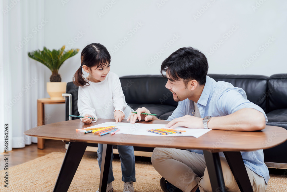 A pair of father and daughter drawing together A pair of father and daughter drawing together