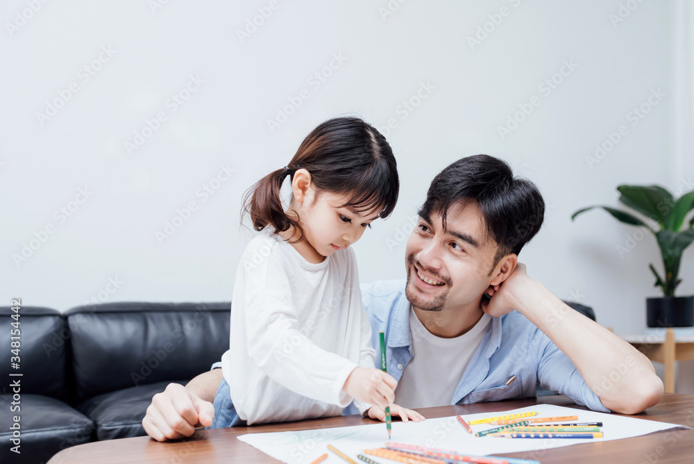 A pair of father and daughter drawing together A pair of father and daughter drawing together