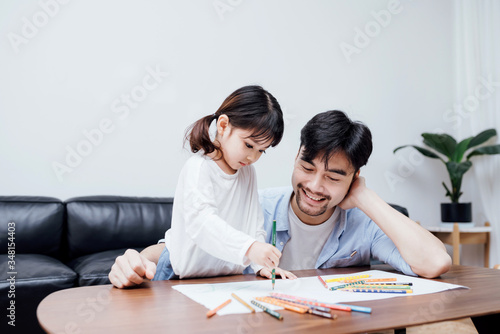 A pair of father and daughter drawing together
