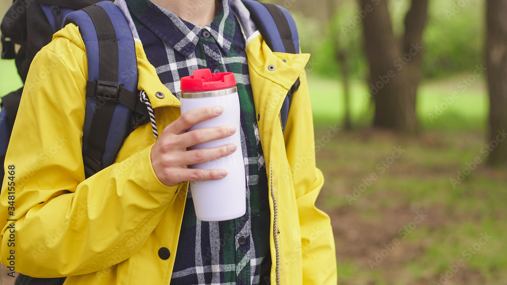 Close up of young tourist woman holding thermos of hot drink, copy space. Travel and hiking concept Close up of young tourist woman holding thermos of hot drink, copy space. Travel and hiking concept