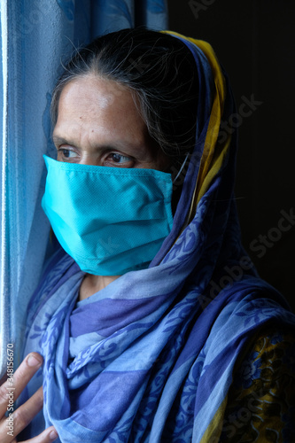 senior asian women with face mask looking through window 