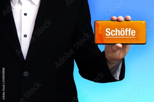 Schöffe. Anwalt zeigt ein Handy. Auf dem Display steht ein Wort. Blauer Hintergrund. Hand hält Telefon. Recht, Gesetz photo