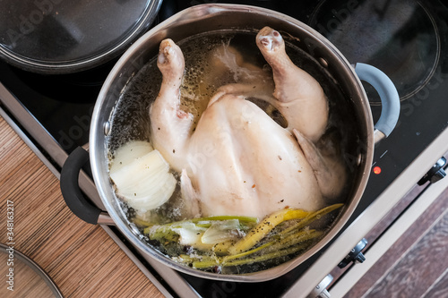 whole chicken in soup cooking in a pan on the stove