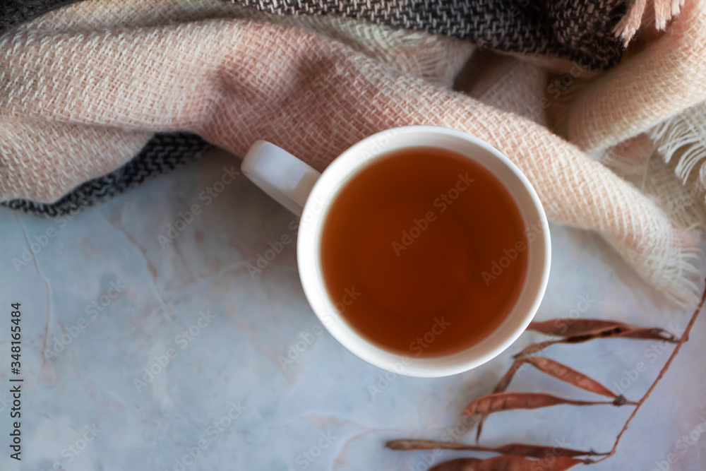 Cozy hot drink autumn mood, top view. Tea in white cup and knitted scarf, autumn leaves Cozy hot drink autumn mood, top view. Tea in white cup and knitted scarf, autumn leaves