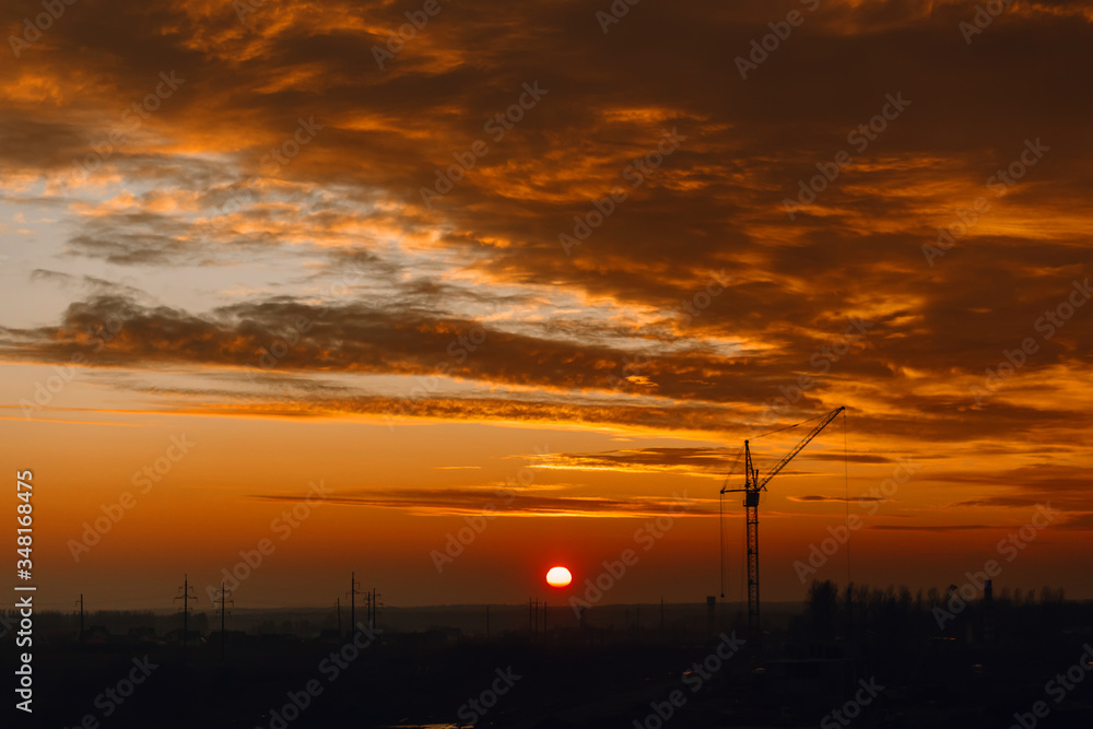 Colorful and bright sunset against the background of construction cranes