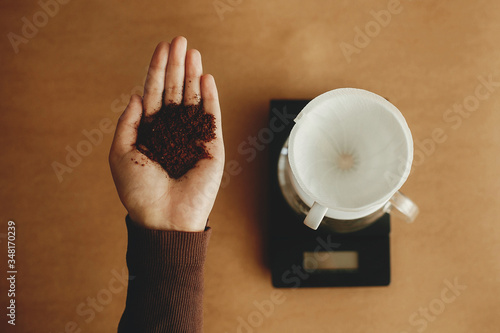 Canvas Print Grind coffee close up in hands on background of glass kettle with pour over on scale