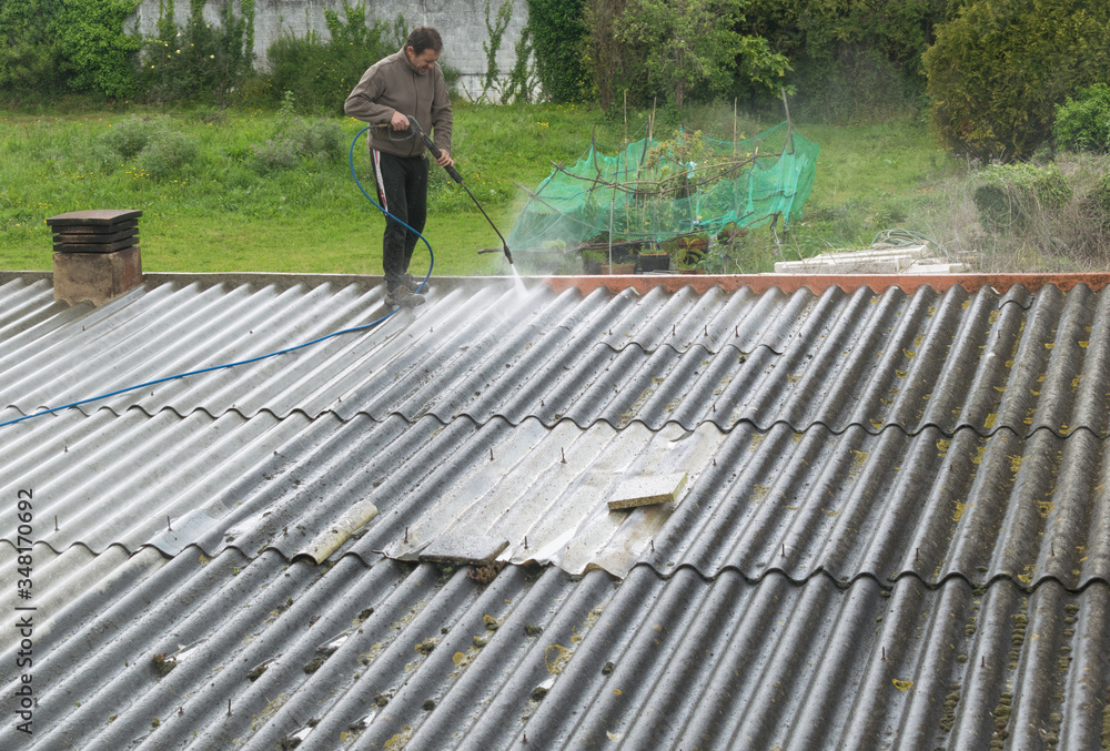 Man cleaning a roof with a pressurized water gun