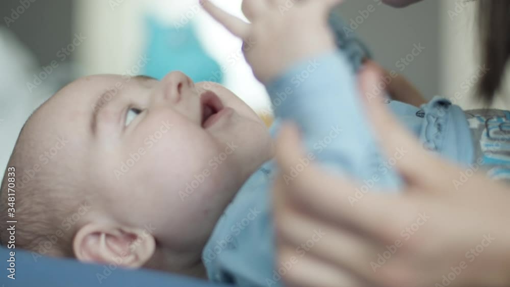 Mother care about her adorable little newborn baby boy. Room indoor scene. Mother care about her adorable little newborn baby boy. Room indoor scene.