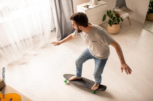 Above view of young man performing balance training on skateboard at home during isolation period © pressmaster